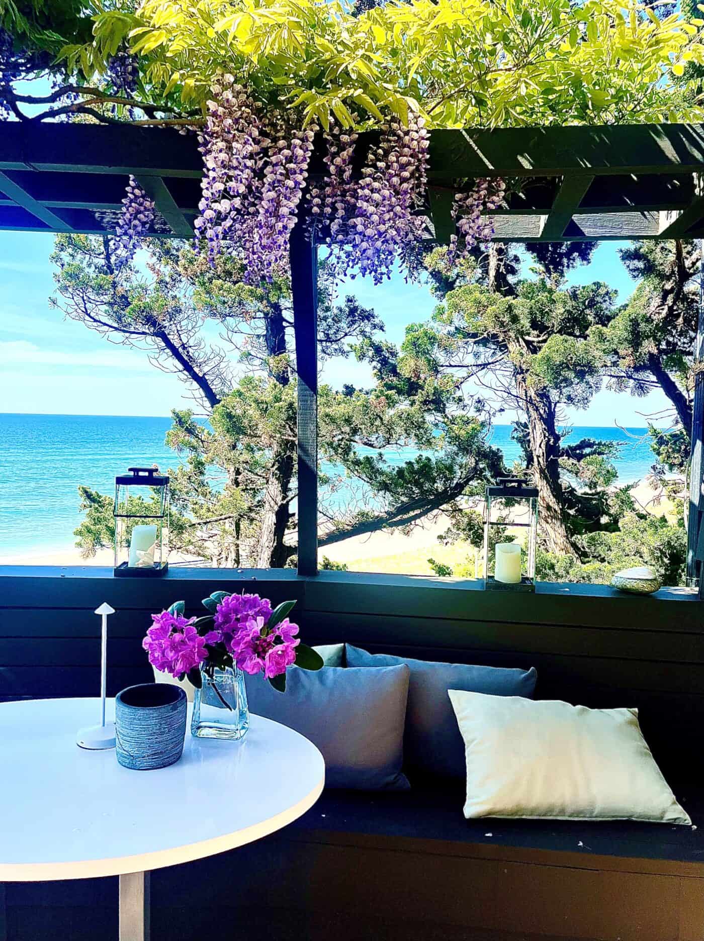 A leafy arbor draped in wisteria shelters an outdoor dining patio.